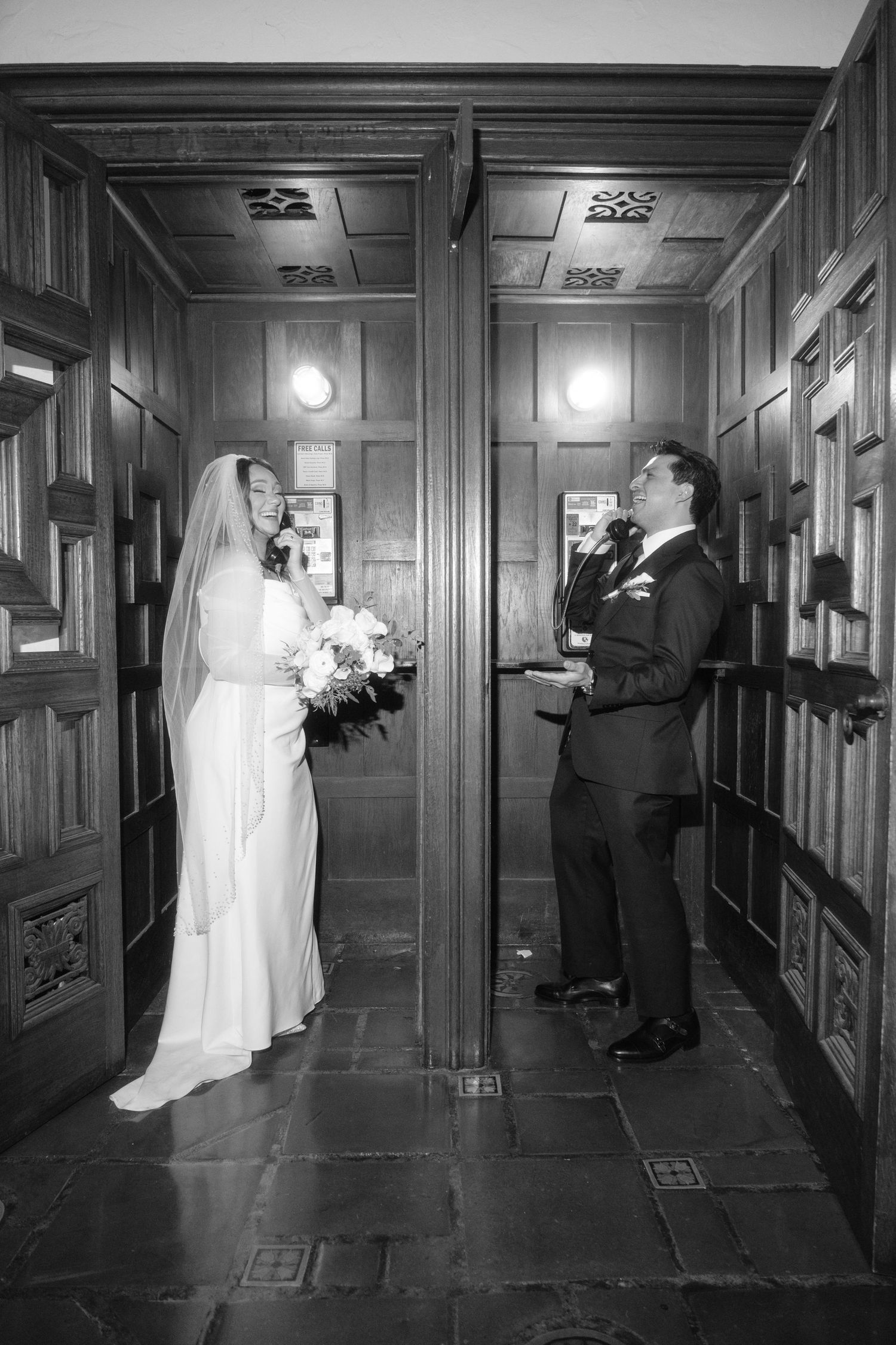 Newlyweds share a candid moment in an elegant wood-paneled hallway during their wedding.