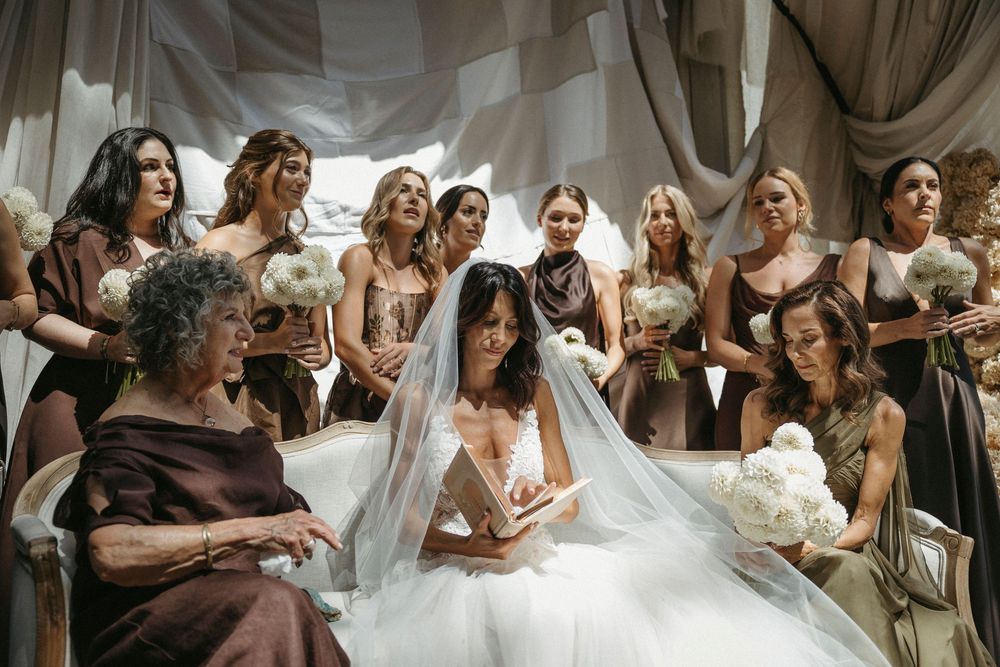 Bride in white tulle gown surrounded by bridesmaids in brown dresses during a wedding ceremony.