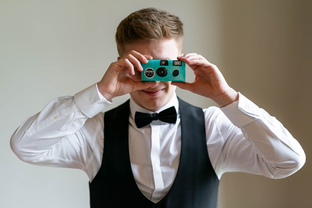 Wedding guest at St Audries Park Wedding venue with disposable camera looking at Matt from Passion 4 Photos