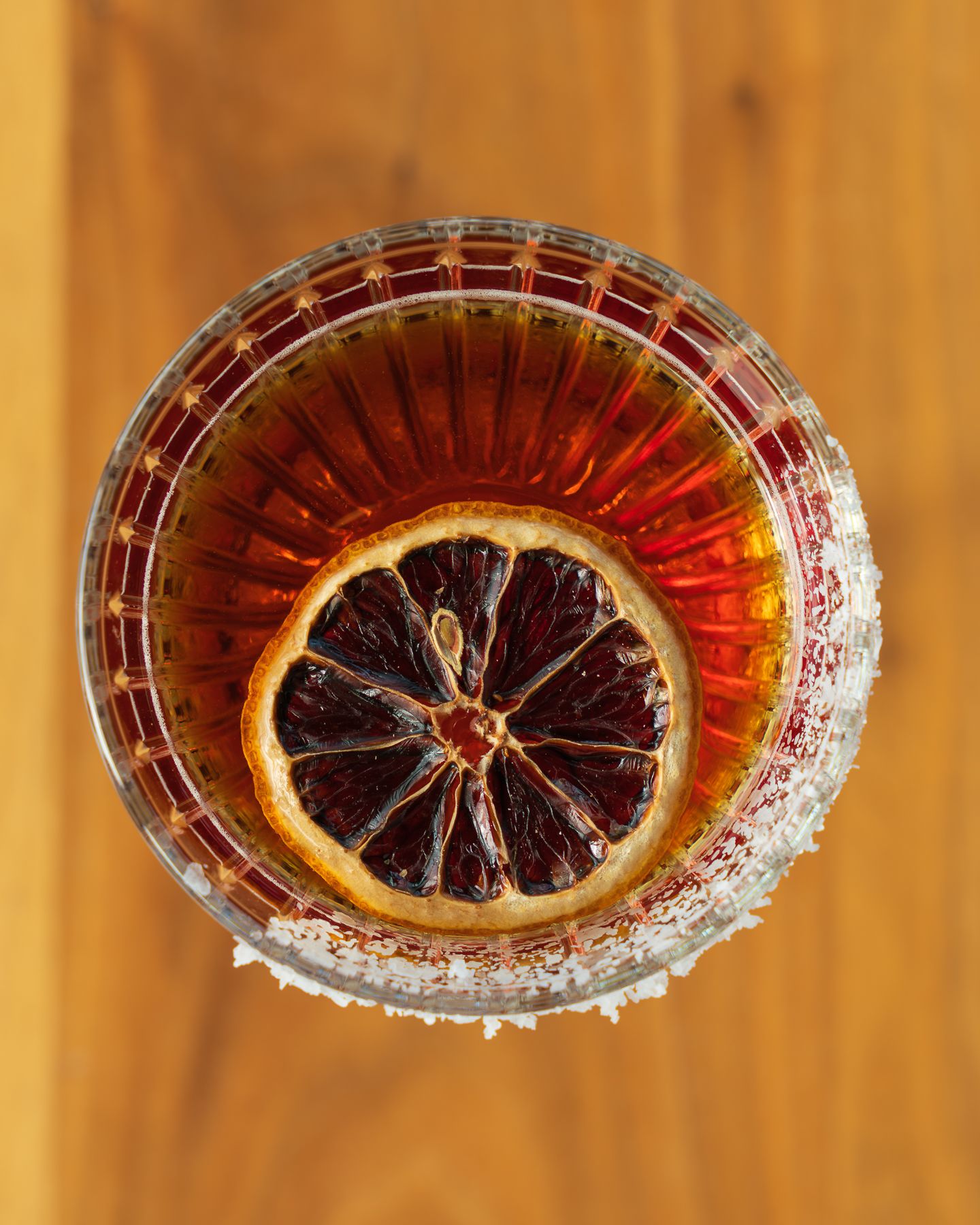 Overhead view of a classic cocktail with dried blood orange slice in a crystal glass.