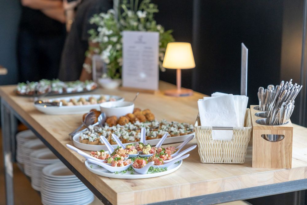 Elegant catering buffet table with assorted appetizers, napkins, and cutlery holder at an indoor event.