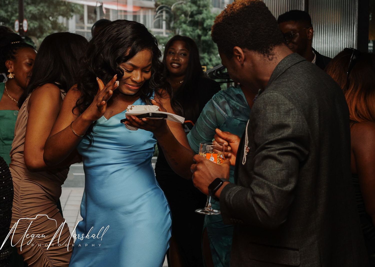 Elegantly dressed guests socializing at a formal event, holding drinks in a stylish indoor venue.