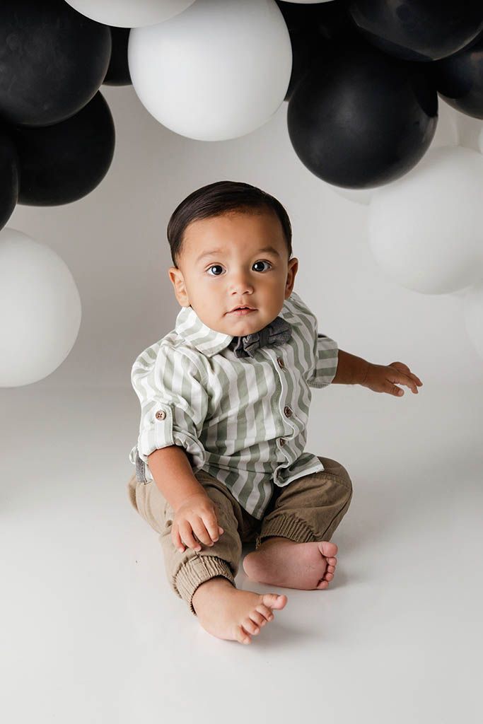 Portrait of a baby boy with black and white balloons by professional Lake Elsinore 1st birthday photographer in California.