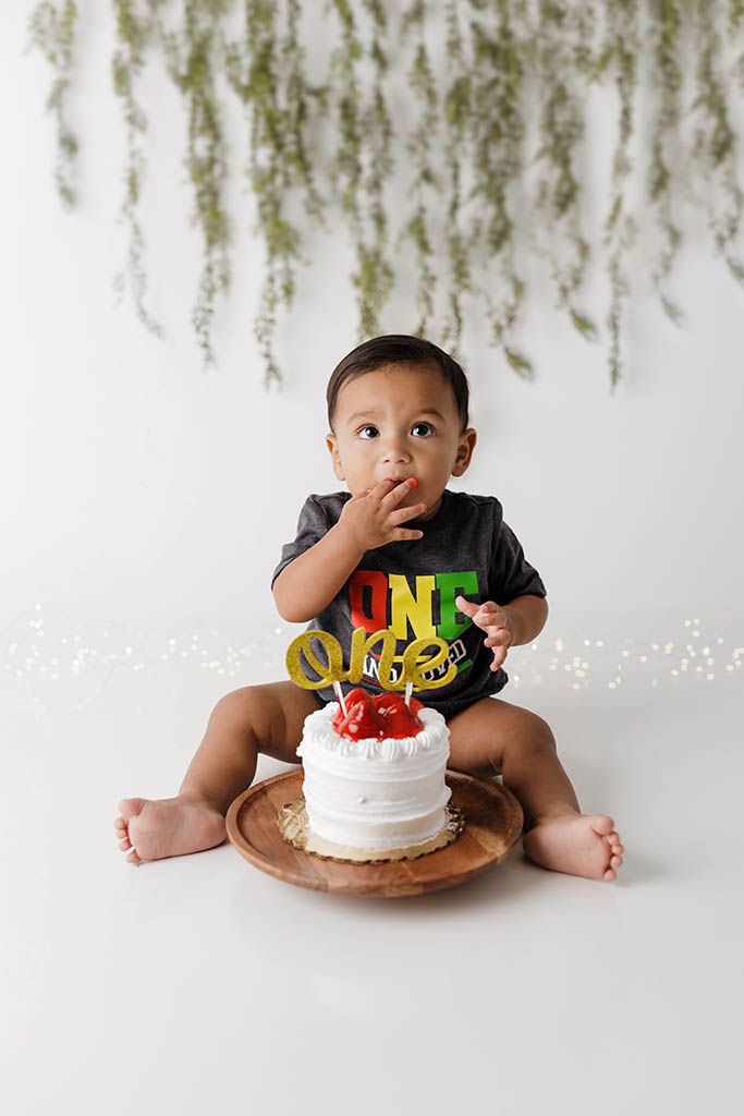 Lake Elsinore 1st birthday photographer photo of baby boy in a ONE AND LOVED onesie sits beside a white smash cake.