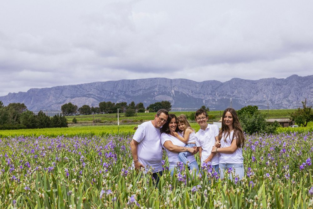 Famille assise dans un champ d’iris avec la Sainte-Victoire en arrière-plan en Provence