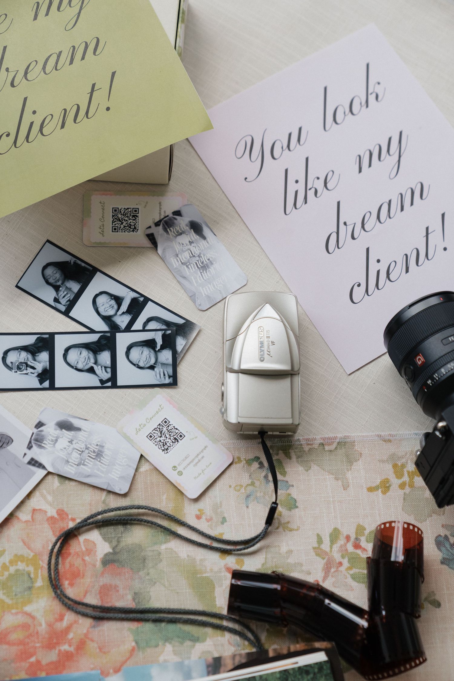 Flat lay of photography business branding with dream client cards, photo strips, camera lens, film roll, and rubber stamp.