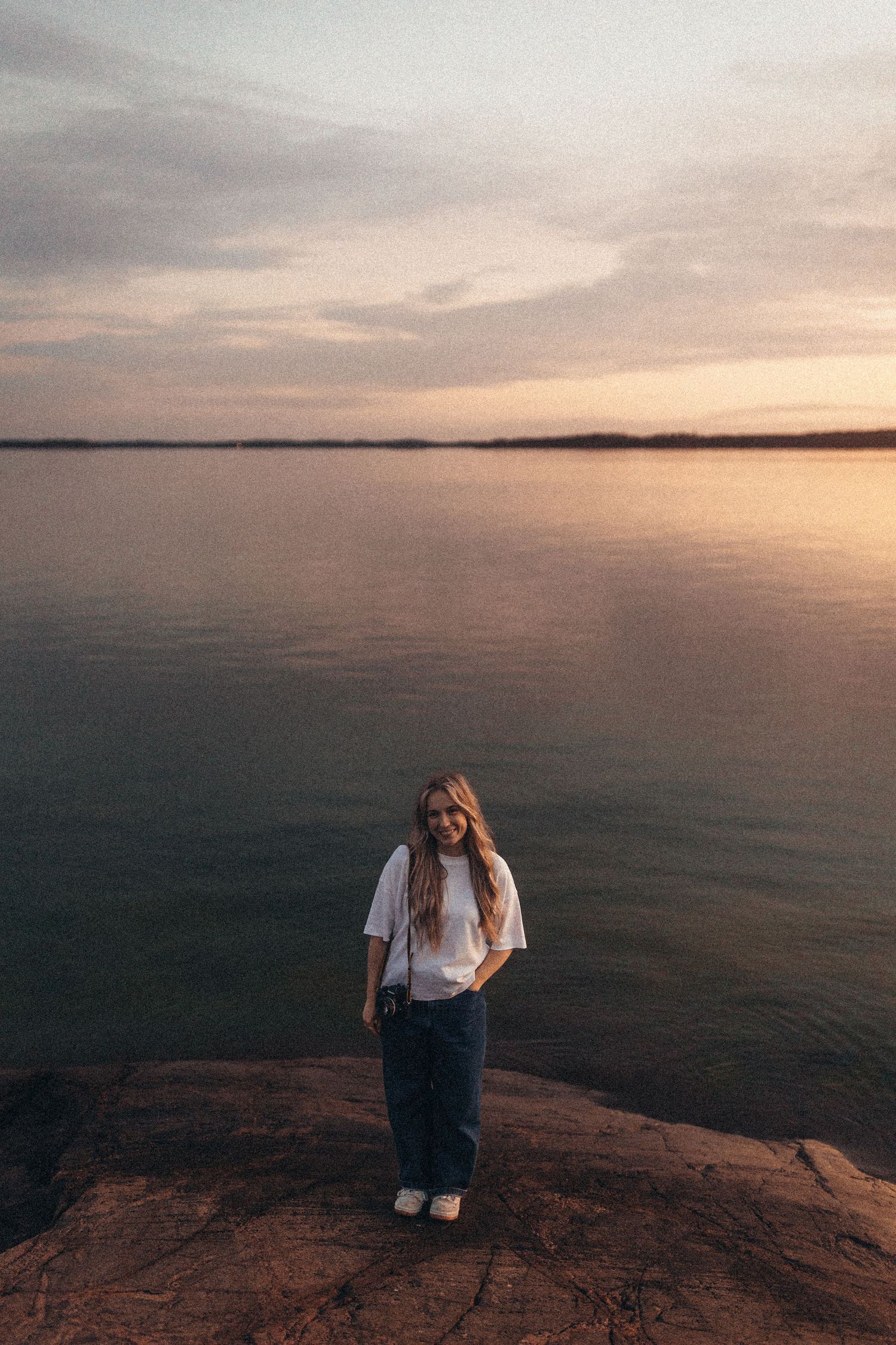 Portrait at sunset with warm golden light and a serene coastal backdrop.