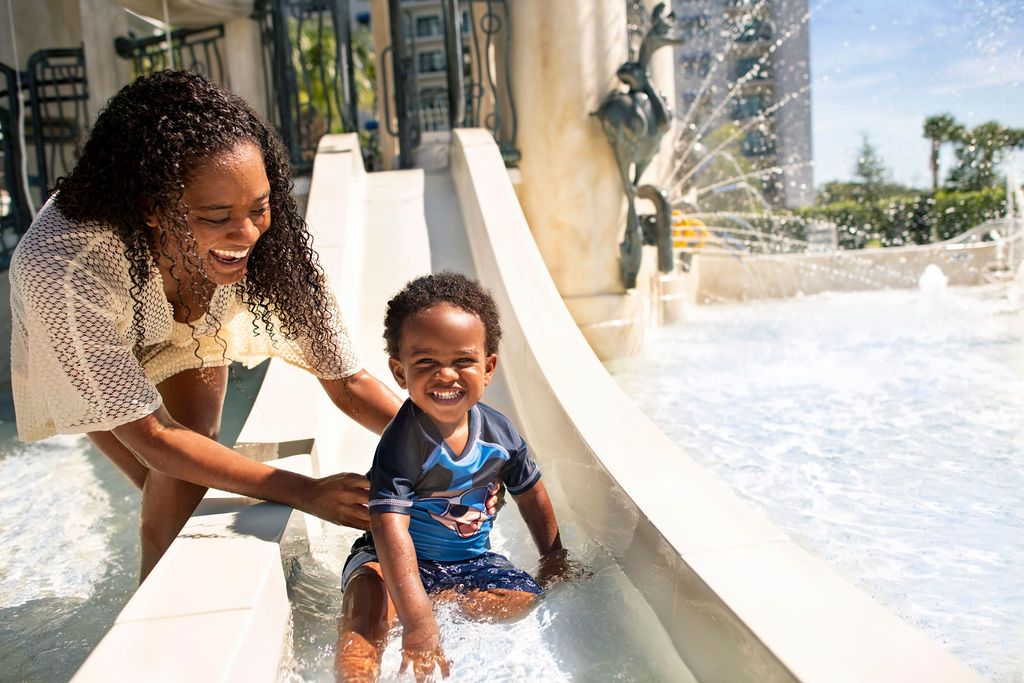 People enjoying a water feature at a Disney resort pool area.