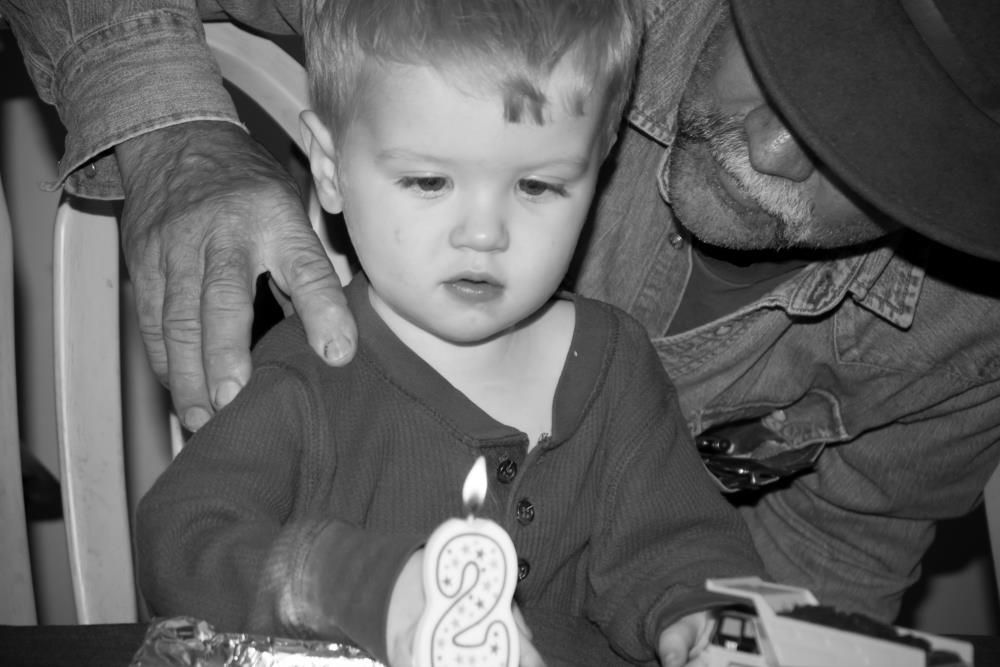 A toddler gets ready to blow out a candle at his 2 year old birthday party.