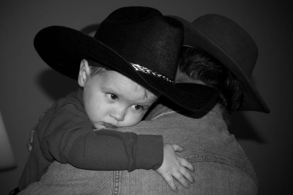 A sleepy toddler cuddles with his grandfather.