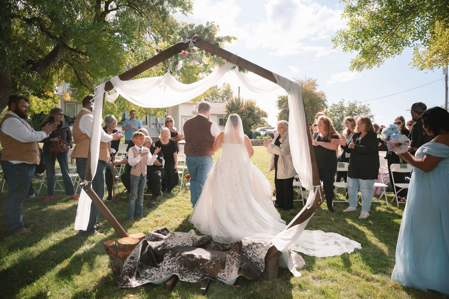 Newlyweds walking down the aisle after their ceremony, surrounded by family and friends.