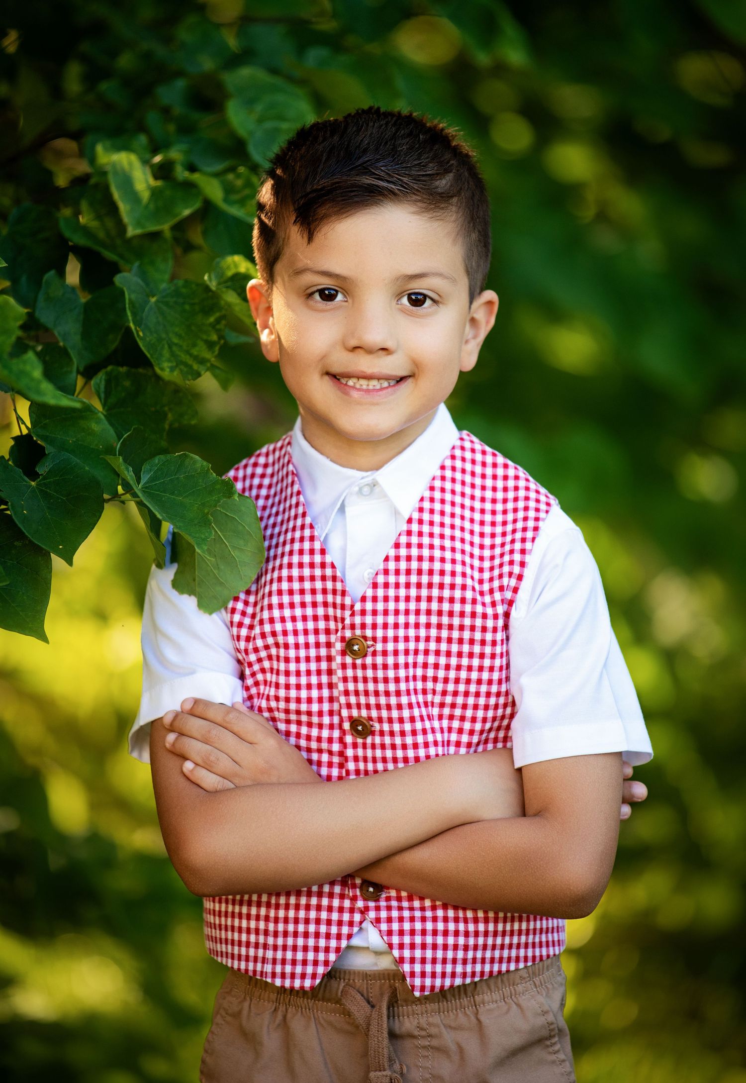 Young child in western cowboy attire with brown vest, white shirt, cowboy hat and jeans against brown backdrop.