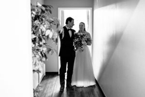 Bride and groom share a tender moment in a hallway in an elegant black and white wedding photo.