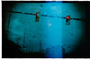 Abstract blue-toned photo of red traffic lights shot through a rain-covered windshield at night.