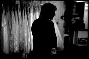 Silhouette of a person standing in a dark room with curtains in the background.