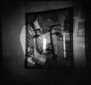 Dark black and white double exposure of a portrait with a candle reflection creating an eerie effect.