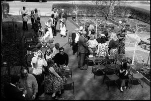 Aerial black and white view of guests mingling at an outdoor wedding reception with patio chairs.