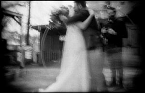 Blurry black and white photo of a bride and groom embracing outdoors.