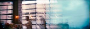 Double exposure color photo of a person near a window with overlapping architectural elements.