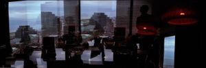 Panoramic silhouette of people seated at a bar with a dramatic city skyline visible through large windows.