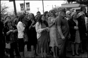 Black and white photo of a large crowd of wedding guests gathered outside on a city street.