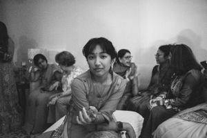 Black and white photo of a woman sitting with a group of women in the background.