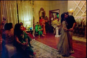 Couple shares a first dance surrounded by guests in a warmly lit decorated room.