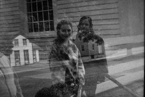 Black and white double exposure of two girls standing near a historic building.