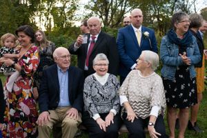 Group of wedding guests posing together outdoors during a daytime celebration ceremony.