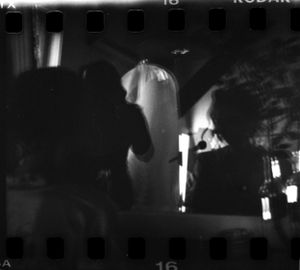 Black and white film strip photo of a bride in veil during a candlelit wedding ceremony.