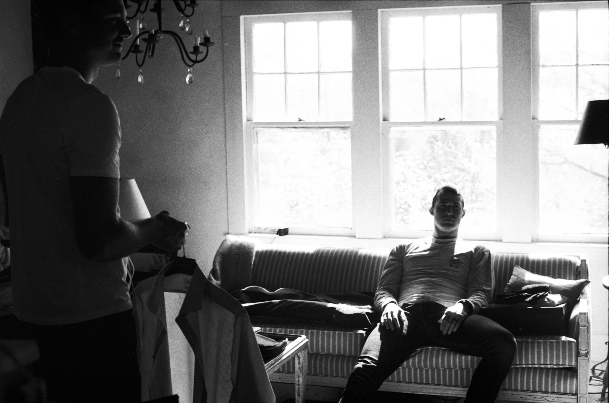 Black and white photo of two people relaxing in a bright living room.