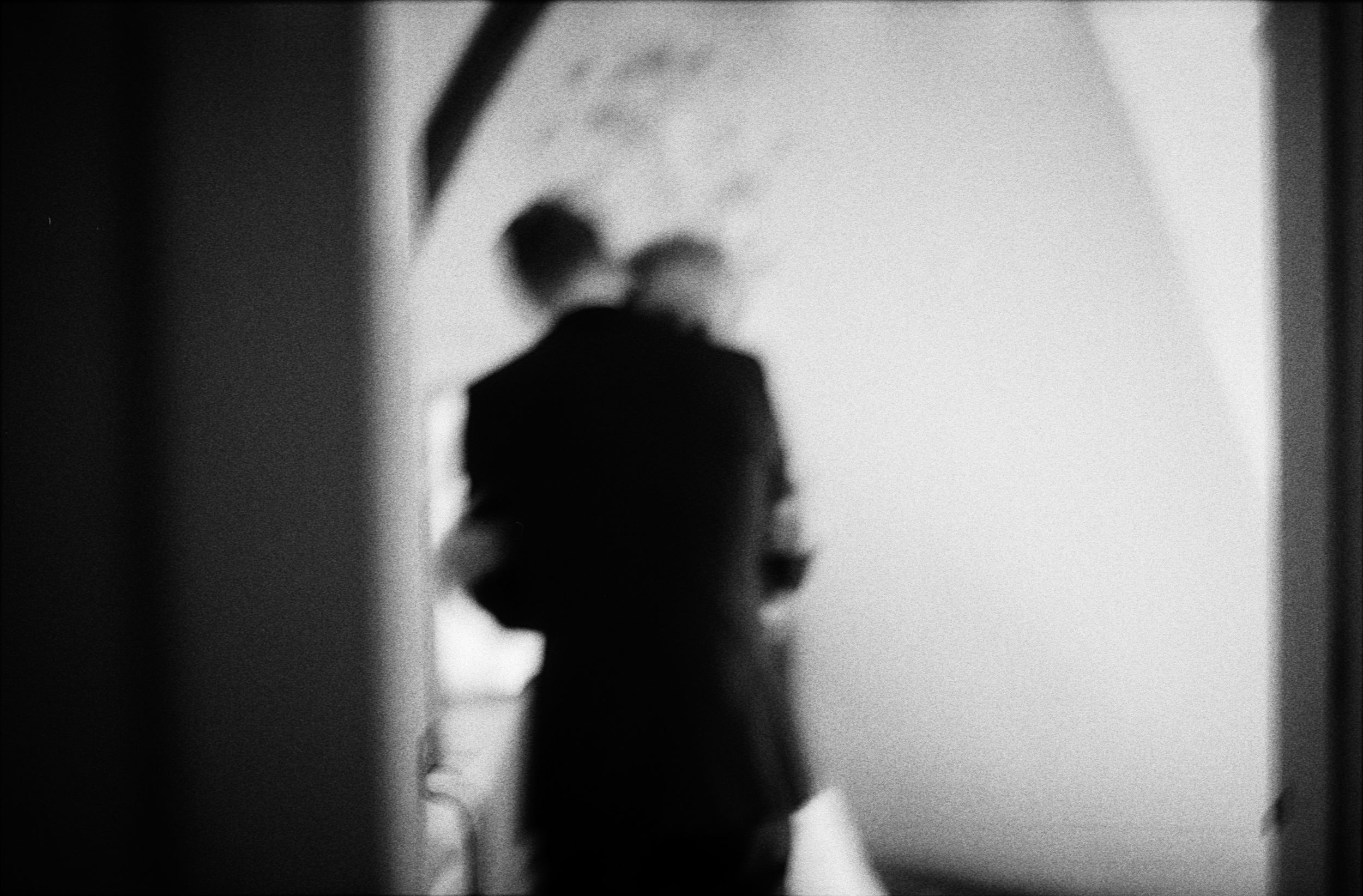 Blurry black and white silhouette of couple embracing in a doorway.