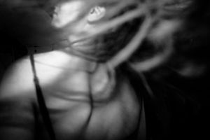 Blurry black and white artistic photo of a woman with hair flying across her face in motion.
