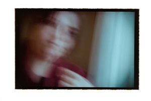 Blurry close-up film photo of a smiling person in a red top.