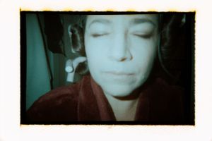 Close-up film photo of a young woman with closed eyes wearing a dark red robe.