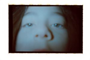Close-up portrait of a young child with blue eyes and soft features in dim light.