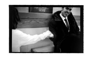 Black and white photo of smiling man in suit shaking hands with woman in casual setting.