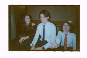 Three young people in formal attire sitting together in a vintage style color photograph.