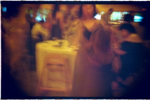 Blurry colorful photo of guests mingling at an indoor reception party.