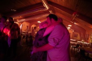 Couple sharing a romantic dance under pink and purple lights at a wedding reception.