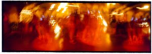 Blurred motion shot of people dancing at a vibrant, warmly lit celebration or party.