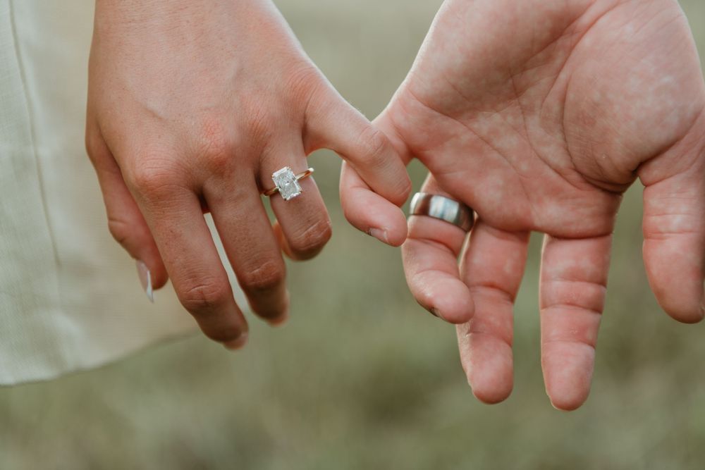 Close-up view of hands wearing wedding rings held together in a romantic outdoor setting. in Boonah Queensland