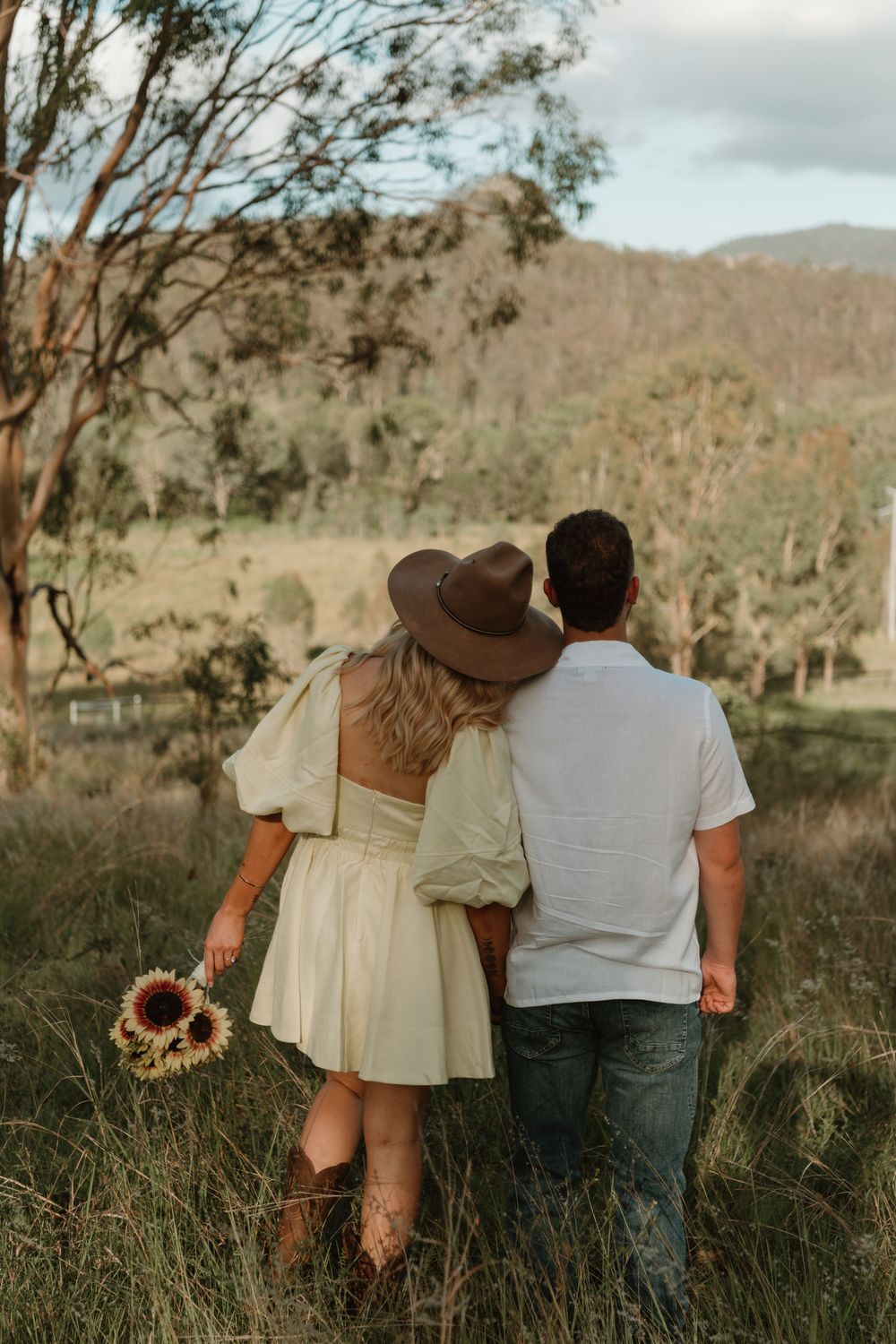 A couple sits together in tall grass at sunset, shown from behind in a series of romantic outdoor photographs.
in Boonah Queensland