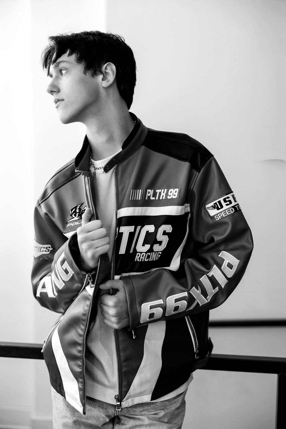 Young man in racing jacket looking away in stylish black and white fashion portrait.
