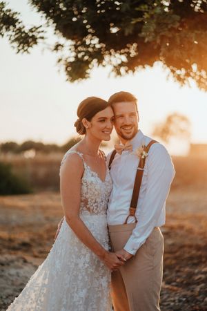 A couple shares joyful moments during their sunset wedding photoshoot in a rustic outdoor setting.