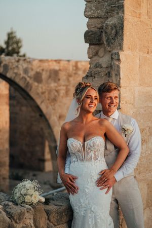 A happy couple shares intimate moments during their sunset wedding photoshoot at a rustic stone venue.