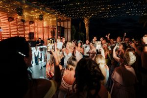 Wedding guests dance and celebrate under twinkling string lights during an evening reception celebration.