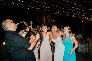 People dancing and celebrating at a nighttime party with string lights overhead creating a festive atmosphere.