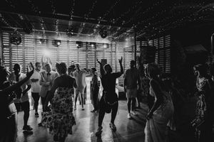 Silhouettes of people walking through a dimly lit indoor space with bright backlighting creating dramatic shadows.