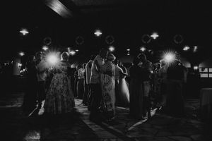 People gather at night under street lights in a dark outdoor setting creating a moody atmospheric scene.